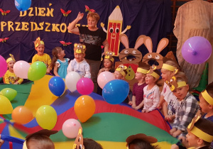 Zabawa z chustą animacyjną i kolorowymi balonikami – dzieci starają się tak manewrować chustą animacyjną, aby baloniki nie spadły na podłogę.